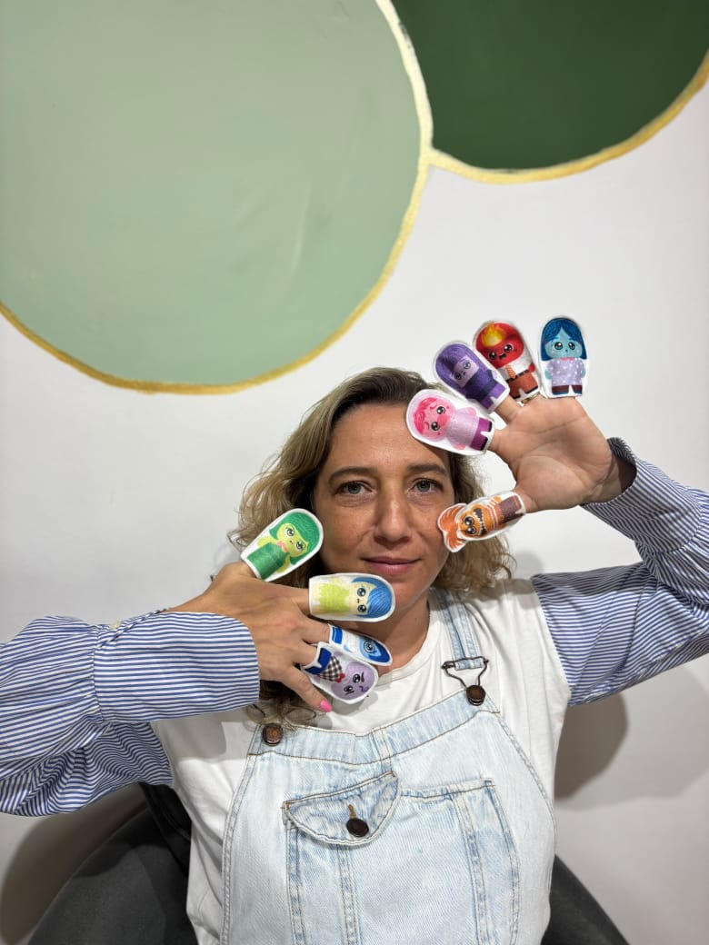 Renata brincando com fantoches de dedo coloridos, recurso usado nos atendimentos infantis