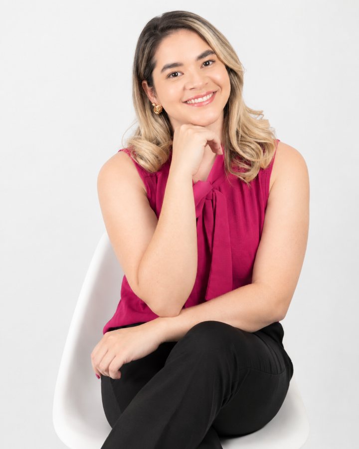 Retrato de Rana Cristina, esteticista, sorrindo, de blusa pink